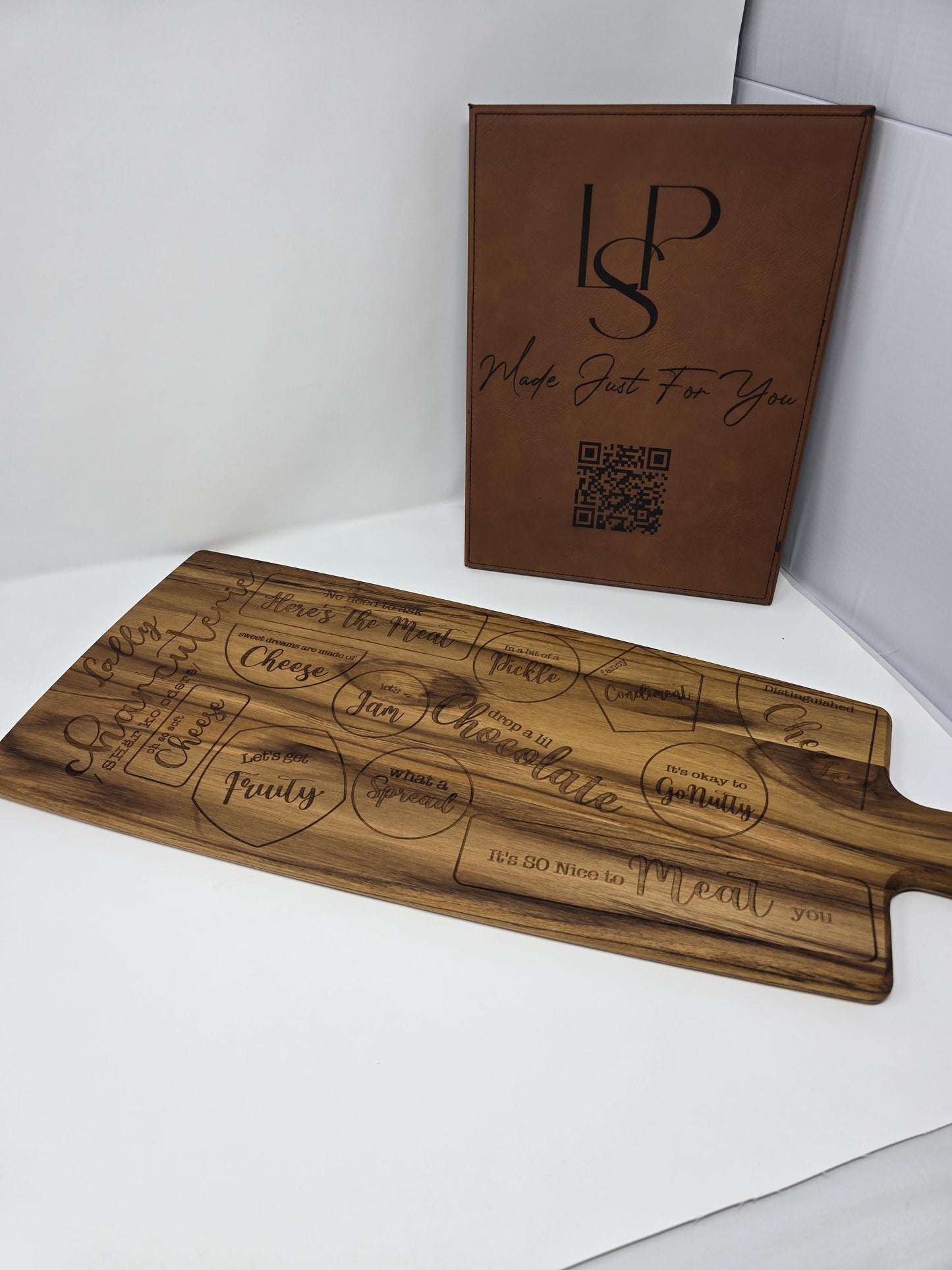 Personalized engraved wooden cutting board with a name and the word "charcuterie" engraved on it, featuring designated spots for meats, cheeses, crackers, and other charcuterie items