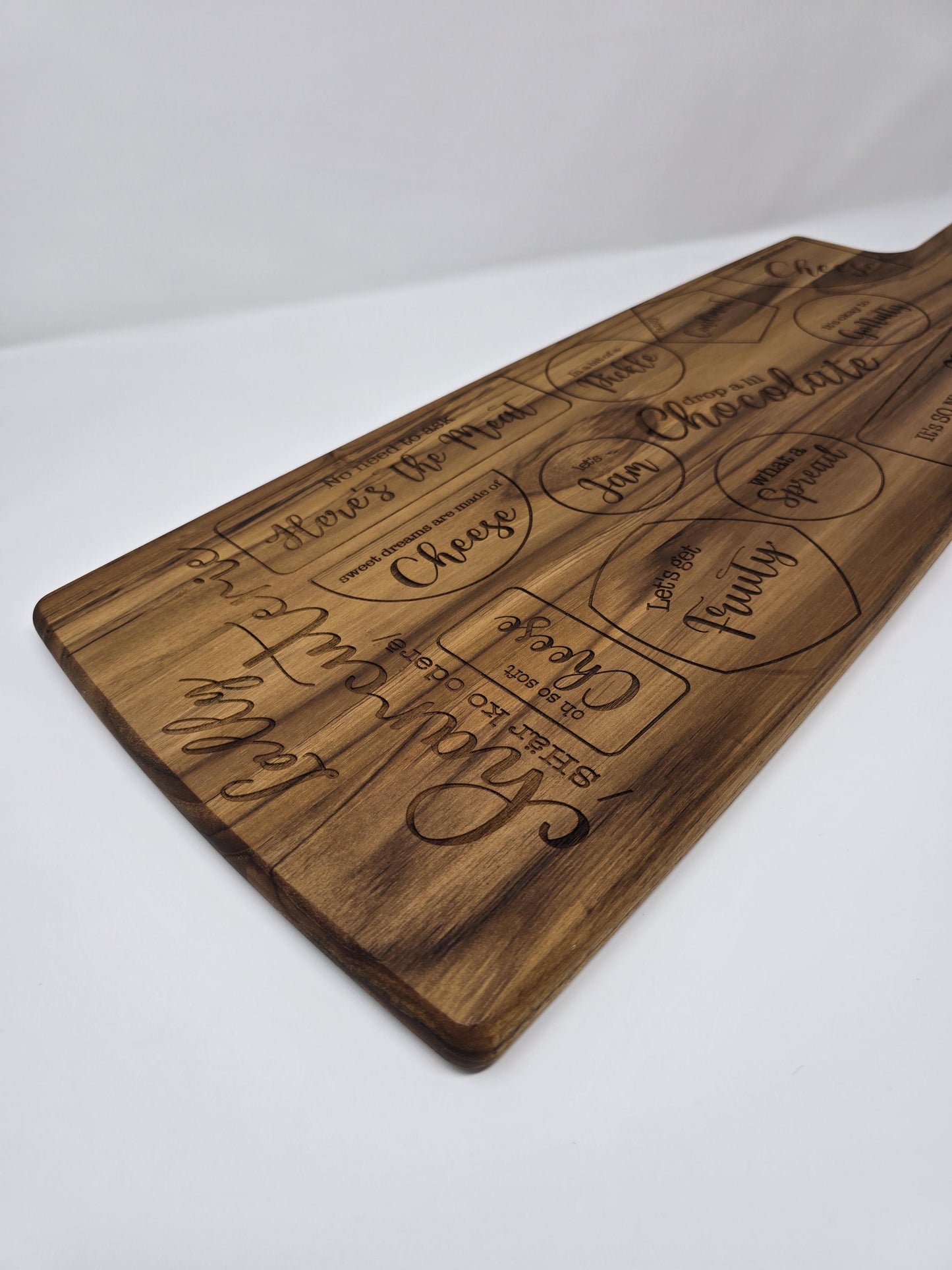 Personalized engraved wooden cutting board with a name and the word "charcuterie" engraved on it, featuring designated spots for meats, cheeses, crackers, and other charcuterie items