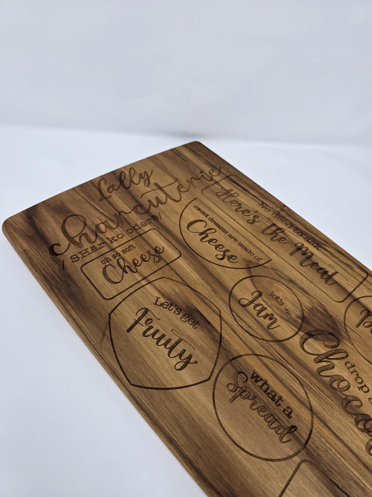 Personalized engraved wooden cutting board with a name and the word &quot;charcuterie&quot; engraved on it, featuring designated spots for meats, cheeses, crackers, and other charcuterie items